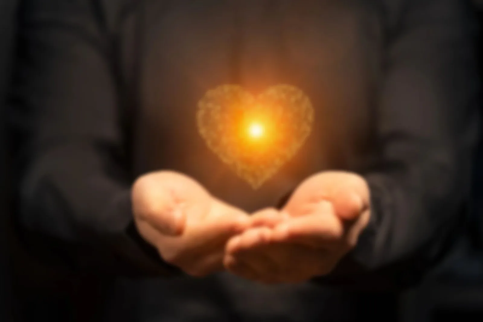 Hands holding a glowing heart, representing care for the community