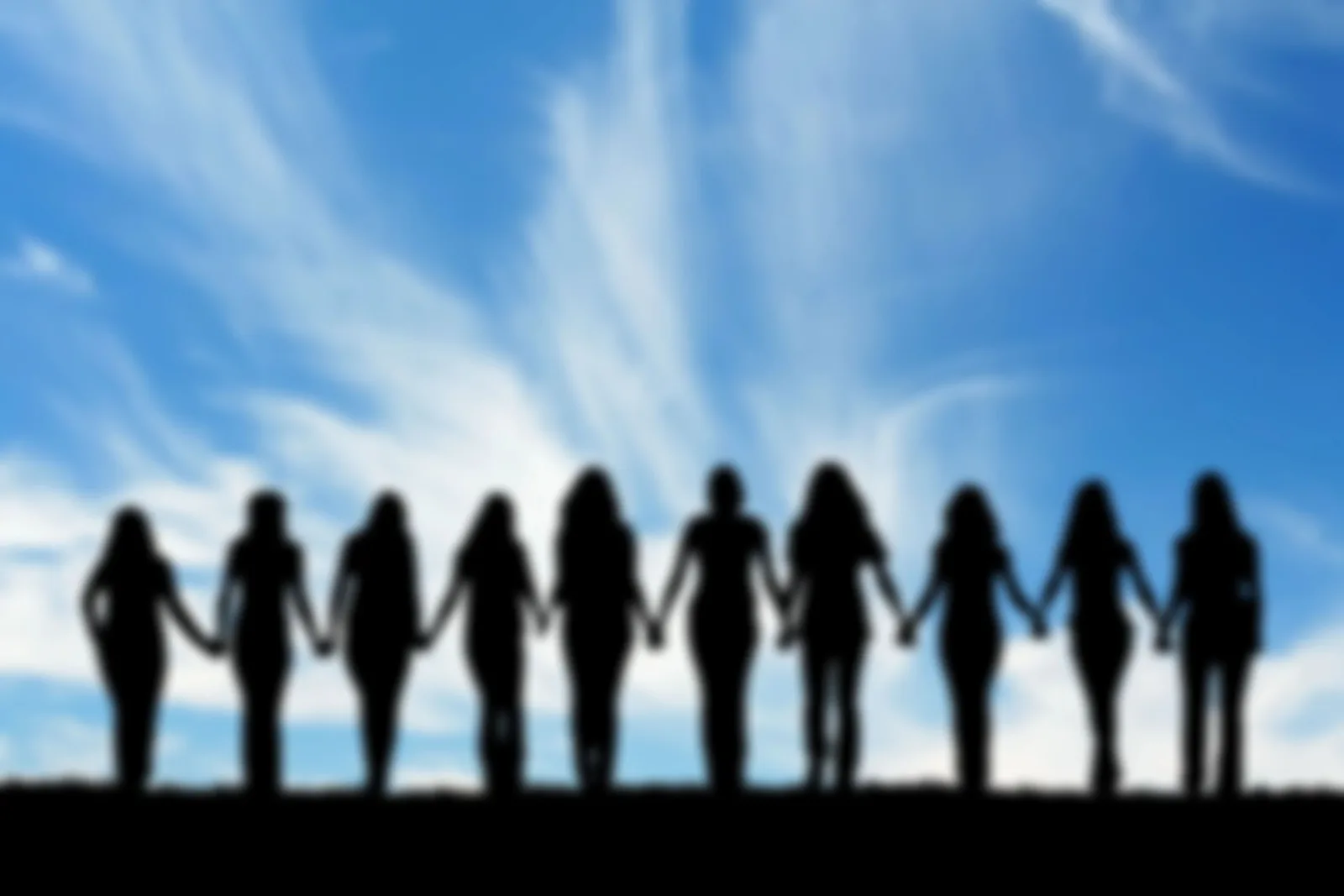 Women standing together beneath a blue sky